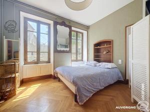 a bedroom with a bed and two windows at Le Chardonneret du Sancy in Montaigut-le-Blanc +6 photos
