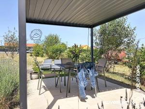 a patio with a table and chairs under a canopy at Le Chardonneret du Sancy in Montaigut-le-Blanc