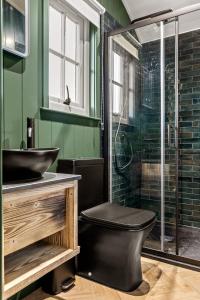 a bathroom with a black toilet and a glass shower at Nestledstays - The Hide in Walberton +96 photos