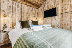 a bedroom with a bed and a tv on a wall at Nestledstays – The Meadow in Binsted