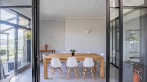 a dining room with a wooden table and white chairs at Sunset Bay Stay in Hout Bay
