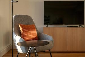 a chair with an orange pillow and a television at 102 - Upscale Condo - River View Terrace in Baie-Saint-Paul