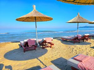 a group of chairs and umbrellas on a beach at Olive Tree Apartment - 290 in Mullini i Danit