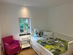 a bedroom with a bed and a pink chair at Fachwerkhaus Eiben in Kirchhundem
