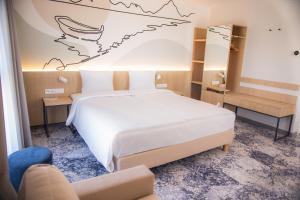 a bedroom with a white bed and a couch at Arche Hotel Lotnisko Gdańsk in Gdańsk-Rębiechowo