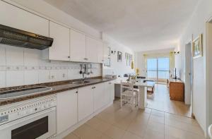 a kitchen with white cabinets and a table in it at oceano de bajamar in Bajamar