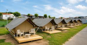a row of tents with chairs and tables at Camping Derby Loredo by Mola! in Loredo