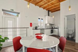 a kitchen and dining room with a white table and red chairs at Casa Albano 3 in Caldas da Rainha