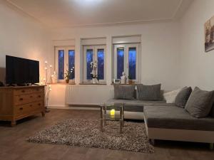 a living room with a couch and a tv and windows at NEU! Kleines Glück Illingen in Illingen