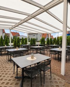 a patio with tables and chairs under a white canopy at Hotel Weinhaus Wiedemann in Ginsheim