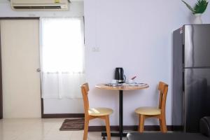 a kitchen with a table and two chairs and a refrigerator at Rangsit Apartment I in Ban Talat Rangsit