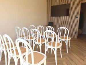 a group of white chairs and tables in a room at Hôtel des Vignes - Juliénas in Juliénas