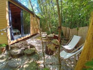 a yard with chairs and a house and trees at La cachette du G in Bellebrune