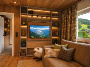 a living room with a couch and a tv at lechner living apartments in Wald im Pinzgau