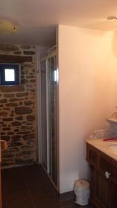 a bathroom with a walk in shower next to a stone wall at Gites laurent in Guissény