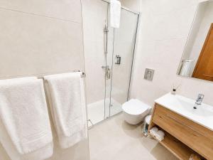 a bathroom with a shower and a toilet and a sink at Luz Sun Poolhouse in Luz