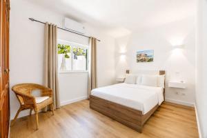 a bedroom with a bed and a chair and a window at Luz Sun Poolhouse in Luz +22 photos