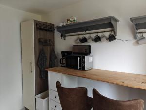 a kitchen with a microwave and a counter with chairs at 3-room vacationapartm Sax Switzerland very basic in Lauterbach