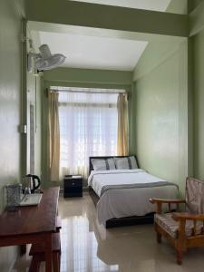 a bedroom with a bed and a desk and a window at Tre Lum Homestay in Jowai