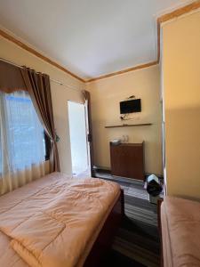 a bedroom with a bed and a tv on the wall at DIENG CAKRAWALA CABIN Tambi Syariah in Kejajar