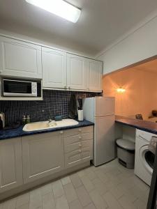 a kitchen with white cabinets and a white refrigerator at Seabreeze T3 in Carvoeiro +8 photos