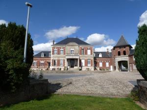 een groot gebouw van rode baksteen met een klokkentoren bij Studio Ferme de Bonavis in Banteux