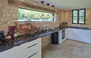 a kitchen with white cabinets and a stone wall at Lovely Home In Clef Vallée D'eure in La Croix-Saint-Leufroy +19 photos