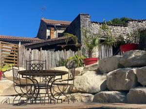 a table and chairs sitting next to a stone wall at La Salamandre Enchantée in Louzac - Saint-André
