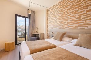 a bedroom with two beds and a brick wall at Hotel Eden Palma Playa Adults Only in Can Pastilla