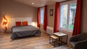 a bedroom with a bed and a couch and windows at La Salamandre Enchantée in Louzac - Saint-André