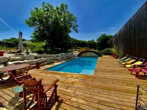 a wooden deck with chairs and a swimming pool at La Salamandre Enchantée in Louzac - Saint-André