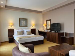 ein Hotelzimmer mit Bett und Fernseher in der Unterkunft Hotel Monogram Park in Ruma