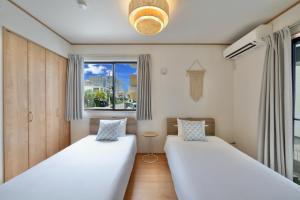 two beds in a room with a window at 北谷町港1 in Chatan