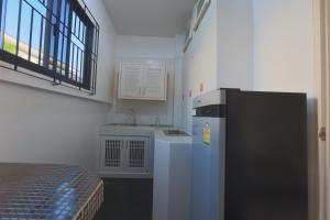a small kitchen with a refrigerator and a sink at Chalong Pool Courtyard in Ban Na Bon