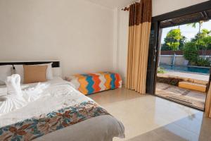 a bedroom with a bed and a large window at Chalong Pool Courtyard in Ban Na Bon