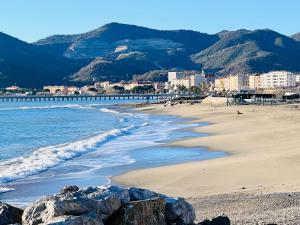 a beach with rocks and the ocean and mountains at Casa Acquarello in Savona