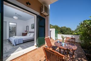 a room with a bed and a table and chairs on a balcony at Villa Verde with Outdoor Jacuzzi in Divarata