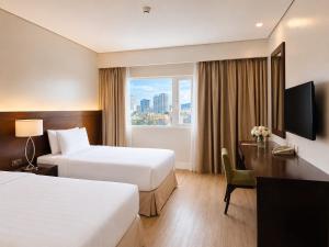 a hotel room with two beds and a desk and a window at Harolds Hotel Cebu in Cebu City +171 photos