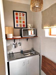 a small kitchen with a sink and a microwave at Riverside Cottages in Graaff-Reinet
