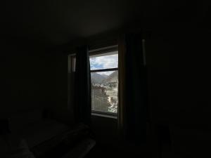 a window in a dark room with a view of a city at Hotel The Kargil Castle in Kargil