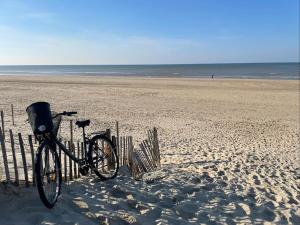 a bike parked next to a fence on the beach at NÜ-DE GITES ET SPA in Zuydcoote