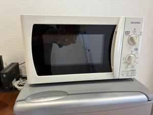 a white microwave sitting on top of a refrigerator at apartment hotel myu in Mito