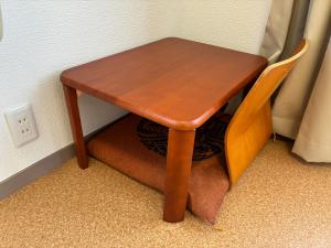 a small wooden table and a chair next to a wall at apartment hotel myu in Mito