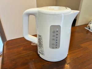 a white coffee pot sitting on top of a table at apartment hotel myu in Mito