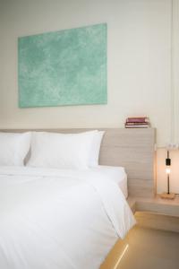 a bedroom with a white bed with a green painting on the wall at Sandana Studio Apartments - Studio 2 in Nathon Bay