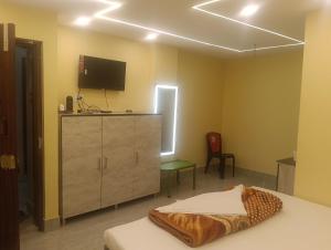 a bedroom with a bed and a dresser with a television at Royal Guest House in Baidyabāti