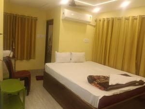 a bedroom with a bed and a chair and a window at Royal Guest House in Baidyabāti
