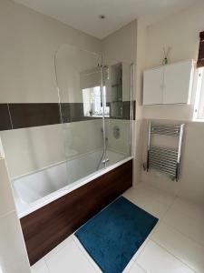 a bathroom with a tub and a blue rug at Modern Private Rooms in Chelmsford with Workspace & Free Parking in Chelmsford