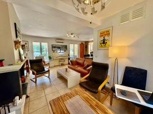 a living room with a couch and chairs and a tv at Les Carnoulettes in Carnoules