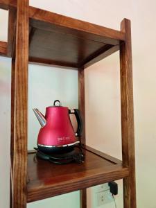 a red tea kettle sitting on a wooden shelf at L'Ananas Garden Homestay in Vũ Lâm